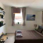 Schlafzimmer mit Bett, Fenstern und Wandbild.