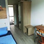 Schlafzimmer mit Bett, Kleiderschrank und Schreibtisch.