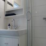 Badezimmer mit Waschbecken, Dusche und Spiegelschrank.