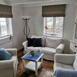 Wohnzimmer mit Sofa, Sesseln und Tisch. Fenster mit Rollladen und Schrank.