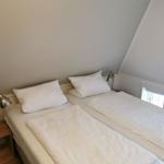 Zimmer mit Doppelbett, zwei Nachttischen und Stehlampe unter Dachschräge.