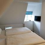 Schlafzimmer mit Dachschrägen, Bett, Fenster und Fernseher.