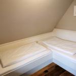 Zwei Betten in einem Dachzimmer mit Holzboden und Wandbild.