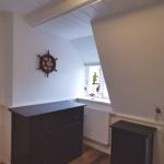 Zimmer mit Schiffssteuerung an der Wand, dunklem Schrank und Fenster mit Spielzeug.