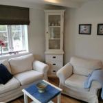 Wohnzimmer mit Sofa, Sessel, Tisch und Glasvitrine.
