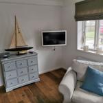 Ein Wohnbereich mit Sofa, Fernseher und Modellboot.