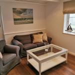 Wohnzimmer mit Sofa, Sessel, Glas-Tisch und Wandbild