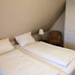 Zimmer mit Doppelbett, Nachttisch, Stuhl und Kleiderschrank.