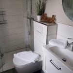 Badezimmer mit Dusche, Toilette und Waschbecken mit Spiegel.