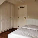 Schlafzimmer mit Bett, Kleiderschrank und Tür