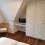 Schlafzimmer mit Dachschrägen, Bett, Schrank, Schreibtisch und Stuhl.