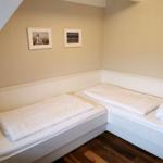 Zwei Betten in einem Dachzimmer mit Holzboden und Bildern an der Wand.