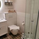 Badezimmer mit Dusche, Toilette und Waschbecken mit Spiegel.