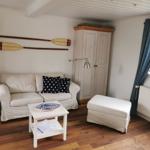 Wohnzimmer mit Sofa, Tisch und Schrank. An der Wand hängen zwei Ruder.