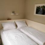 Schlafzimmer mit Doppelbett, weißen Bettwäsche und Wandbild.