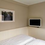 Schlafzimmer mit Bett, Fernseher und Wandbild.