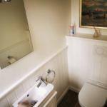 Badezimmer mit Waschbecken, Spiegel, Toilette und Wandbild.