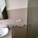 Badezimmer mit Dusche, Waschbecken und Handlauf