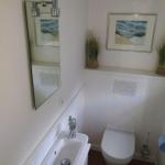 Badezimmer mit Toilette, Waschbecken und Spiegel an der Wand.