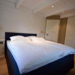 Schlafzimmer mit Doppelbett, weißen Nachttischen und Kleiderschrank.