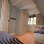 Zimmer mit Dachschrägen, Bett, Kleiderschrank und Fenster mit Blick.