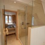 Dusche mit Glaswand und Sauna im Hintergrund