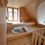 Holzsauna mit Sitzbänken, Fenstern und Handtuchstapeln.