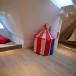 Dachgeschosszimmer mit Spielzelt, Hängesessel und Fenster