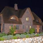 Haus mit strohgedecktem Dach und Steinmauer im Garten