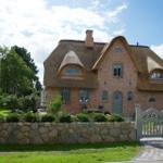 Ein Haus mit Strohdach, Backsteinfassade und Steinmauer mit Tor.