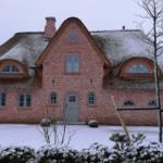 Rotes Backsteinhaus mit Strohdach und Schnee