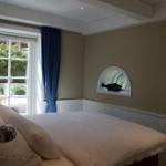 Schlafzimmer mit Bett, Fenster und zwei Bogenfenstern.
