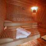 Sauna mit Holzbank, Handtuch und Thermometer an der Wand.