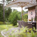 Terrasse mit Tisch, Stühlen und Sonnenschutz neben Backsteinhaus.
