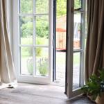 Durch offene Fensterblick auf Garten mit Lavendel und Holzterrasse