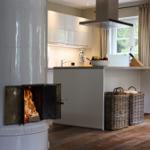 Küche mit weißer Arbeitsplatte und Kaminofen mit brennendem Holz.