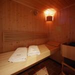 Sauna mit Holzbank, zwei Handtüchern und Wandbeleuchtung.
