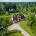 Haus mit Strohdach und Garten. Umgeben von Wald und Grünflächen.