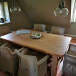 Esszimmer mit Holztisch, sechs Stühlen und zwei Deckenleuchten.