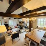 Wohn- und Essbereich mit Kamin, Holztisch und Balken.