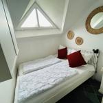 Schlafzimmer mit Dachschräge, Fenster und Bett mit Kissen.