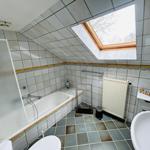 Badezimmer mit Dusche, Badewanne, Toilette und Waschbecken unter Dachschrägen mit Dachfenster.