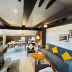 Wohn- und Essbereich mit Holzbalken, Sofa mit gelben Kissen und Kachelofen.