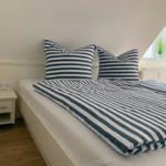Schlafzimmer mit Bett, Kissen und Nachttisch unter schräger Decke.