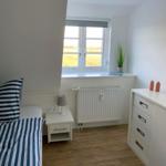 Schlafzimmer mit Bett, Nachttisch und Schrank. Fenster mit Blick auf Feld.