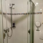 Dusche mit Glaswand, Duschbrause und dekorativer Fliesenserie