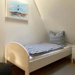 Ein Schlafzimmer mit einem Bett, Nachttisch und Wandbild.