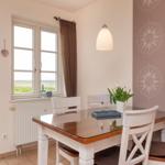 Esszimmer mit Tisch, Stühlen und Fensterblick auf Grünland.