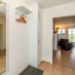 Hausflur mit Kleiderhaken, Schrank und Blick in Wohnzimmer.