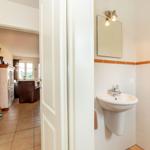 Badezimmer mit Waschbecken und Spiegel. Durchgang zum Wohnzimmer mit Sofa.